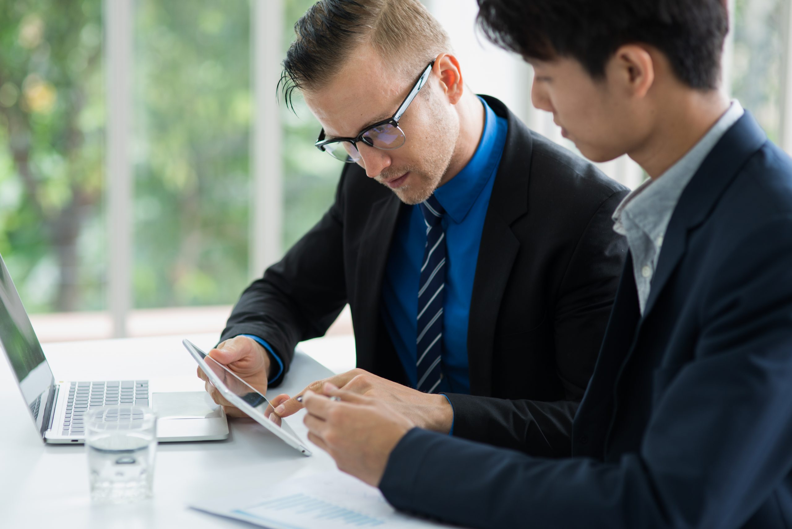 Employees discussing a project and referring to tablet computer